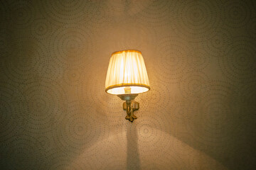 Yellow decorative lampshade with metal body on old dotted wallpaper