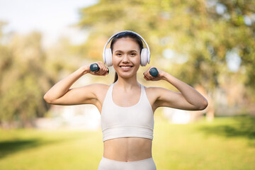 Radiant young woman wearing white workout clothes and headphones enjoys a sunny day