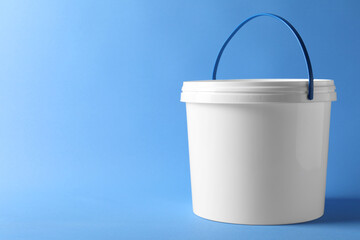 One plastic bucket with lid on light blue background. Space for text