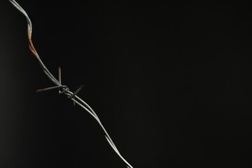 Metal barbed wire on black background. Space for text