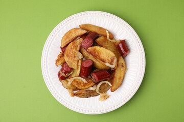 Delicious baked potato with thin dry smoked sausages and onion on green table, top view