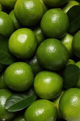 Fresh ripe limes and leaves as background, top view