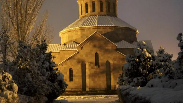 Beautiful Surb Sargis (Saint Sarkis) Armenian apostolic church covered with snow during a winter evening in Nor Nork district in Yerevan, with foreground trees, tilt up, uhd, 4k, 3840, 2160