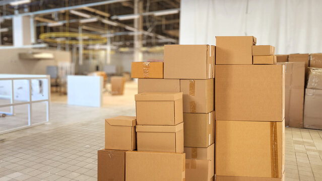 Cardboard boxes in building under construction. Stack of parcels without label. Boxes inside future office building. Concept of moving commercial company. Office changing company boxes