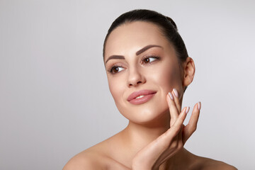 Beautiful young woman with clean fresh skin touch own face. Facial  treatment. Skin care. Cosmetology, beauty and spa.