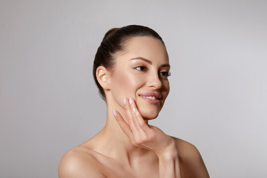 Beautiful young woman with clean fresh skin touch own face. Facial  treatment. Skin care. Cosmetology, beauty and spa.