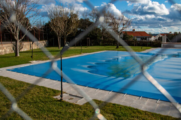 Fototapeta na wymiar Swimming pool covered with a blue tarp ready to spend the winter