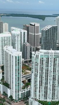 Miami Brickell. Urban landscape of downtown district with high skyscraper buildings and street with cars. Atlantic Ocean on horizon. Aerial view. Vertical video.