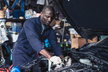 Black car mechanic man fixing and changing vehicle engine in repair shop