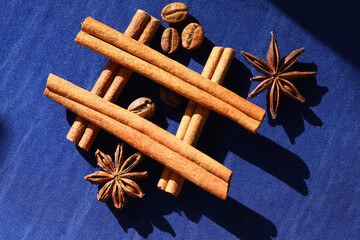 Coffee beans, star anise an cinnamon spices on deep blue background