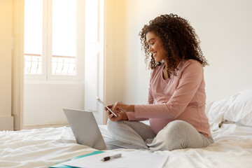 Home Office. Black Pregnant Woman Working With Smartphone And Laptop At Home