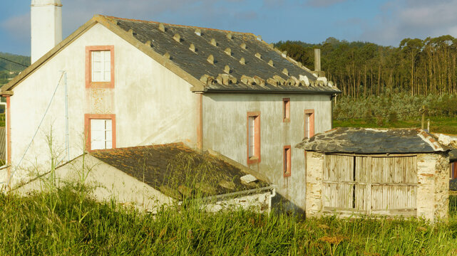 A small village with a horreo surrounded by forests, fields and mountains.