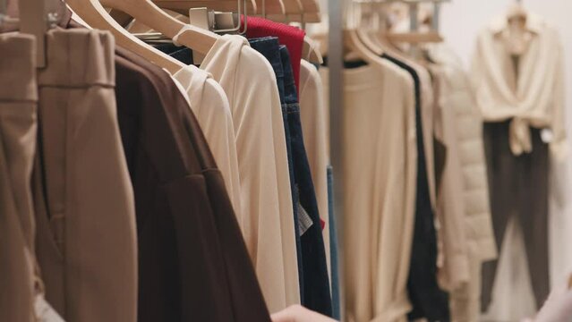 Female hands choosing clothes in a clothing store shop. Shopping concept.