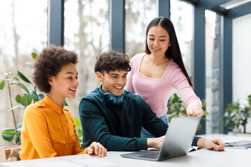 Students interacting over laptop at table