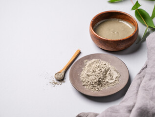 Blue clay in a bowl on a light background with branch and napkin. Concept for preparing homemade skincare organic cosmetics