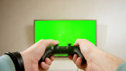 Close-up of a gamer's hands playing a competitive video game on a green chromatic TV screen.