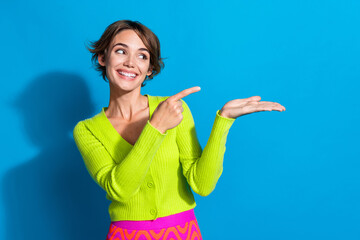Portrait of gorgeous cheerful person look indicate finger hand hold empty space isolated on blue color background