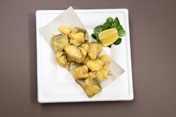 frittura di baccalaà servita in un piatto di carta con limone e insalata - 755826367