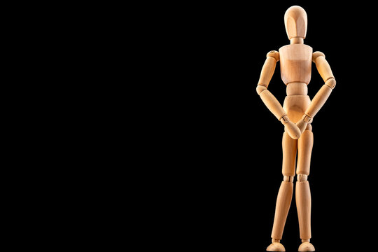 Holzfigur als Symbol f&uuml;r Scham, Nacktheit oder Inkontinenz vor schwarzem Hintergrund