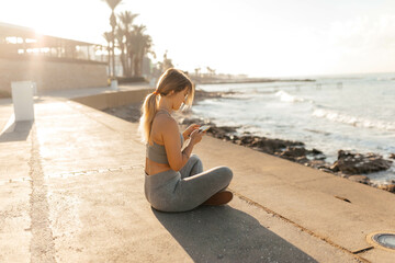 woman sitting on the beach meditating and holding a phone