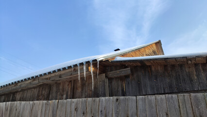 Sharp icicles from melted snow hanging from eaves of roof. Beautiful transparent icicles. Icicles on the eaves of the house