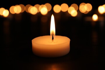 Burning candle on dark surface. Memory day