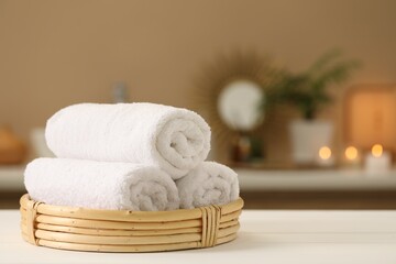 Spa composition. Rolled towels on white table indoors. Space for text
