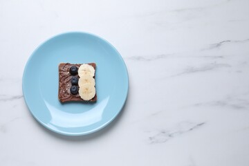 Toast with tasty nut butter, blueberries, banana and nuts isolated on white marble table, top view. Space for text
