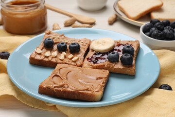 Different tasty toasts with nut butter and products on table, closeup