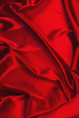Red silk or satin luxury fabric texture can use as abstract background. Top view.