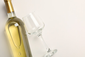 Bottle of expensive white wine and wineglass on light background, top view. Space for text