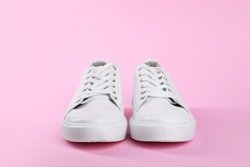 Pair of stylish white sneakers on pink background