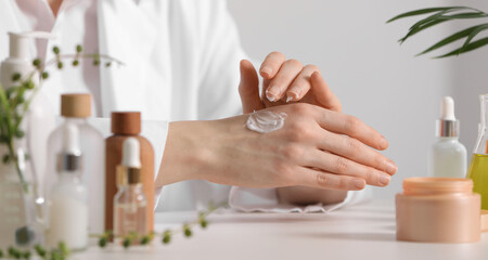 Obraz na płótnie Canvas Dermatologist applying cream onto hand at white table indoors, selective focus. Testing cosmetic product