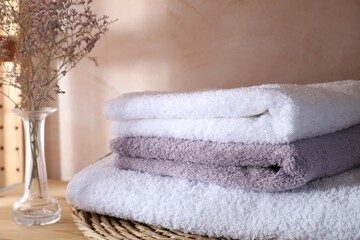 Stacked soft towels and flowers on shelf indoors, closeup