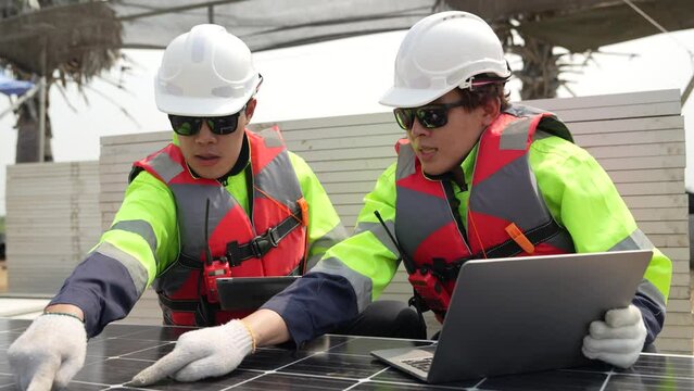 engineer men inspect modules of photovoltaic cell panels. Industrial Renewable energy of green power. workers prepare materials before construction on site with the stack of panels at background.