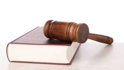 Wooden gavel and book on light table against white background