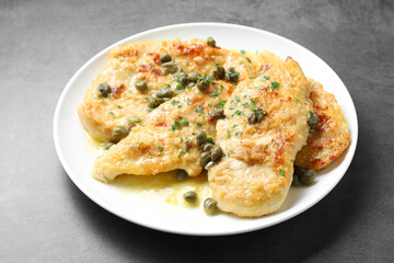 Delicious chicken piccata with herbs on grey table, closeup