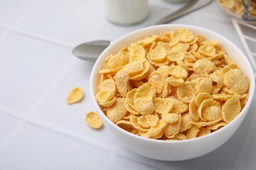 Breakfast cereal. Tasty crispy corn flakes in bowl on white tiled table, closeup. Space for text