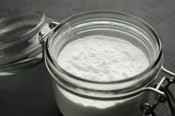 Baking powder in jar on black table, closeup