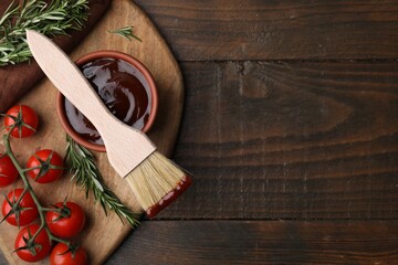 Marinade in bowl, basting brush, tomatoes and rosemary on wooden table, flat lay. Space for text