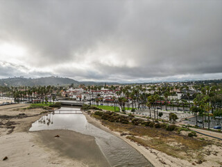 Fototapeta na wymiar Mission Creek spilling into the Pacific Ocean at East Beach along Cabrillo Blvd., State Street, and Stearns Wharf after rainfall on a cloud covered, stormy afternoon in Santa Barbara, California.