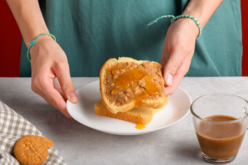 Female hands holding a sandwich with honey and peanut butter spreading on piece of white bread toast, close up. Typical snack food, food lifestyle, domestic life, american breakfast