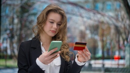 Female using smartphone on daily basis. Young business woman holding smartphone and credit card, typing bank number in app, buying online.