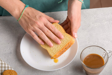 Female hands making a sandwich with honey and peanut butter spreading on piece of wheat bread, to have a breakfast. Typical snack food, food lifestyle, domestic life, american breakfast