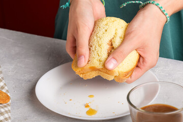female hands breaking a sandwich with honey and peanut butter of wheat bread on white plate, to have a breakfast, close up. Typical snack food, food lifestyle, american breakfast, ready to eat