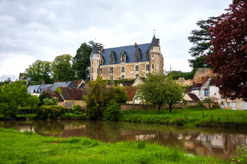 Fototapeta na wymiar Picturesque view of Montresor village with its old castle and Indrois river in moody spring day. Indre-et-Loire, France. Montresor is listed as one of most beautiful villages in France. 
