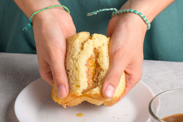 woman's hands breaking a sandwich with honey and peanut butter of wheat bread on white plate, to have a breakfast, close up. Typical snack food, food lifestyle, american breakfast, ready to eat