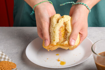 female hands breaking a sandwich with honey and peanut butter of wheat bread on white plate, to have a breakfast, close up. Typical snack food, food lifestyle, american breakfast, ready to eat