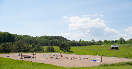 outdoor riding ring with show jumping jumps set up in open field blue sky on nice summer day on...