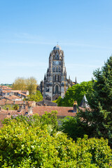 View of historic city of Saintes known from Roman times. Charente-Maritime, France. Old city red tiled roofs drowned in greenery of trees; cathedral at background. Architecture, environment, heritage